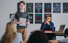 Middle school boy stands in class to do a presentation