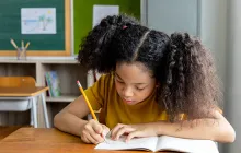 Girl by window writing in a notebook