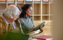 Woman reading in library with other adults