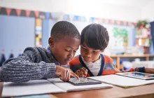 Two young students working together over an iPad
