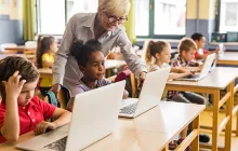 Teacher with young students on laptops