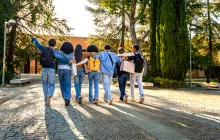 Teens walking arm in arm toward school building