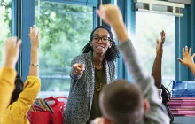 Young teacher with students raising their hands
