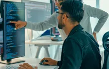 Man with colleague examining code on computer