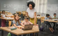 Elementary teacher with students over laptop