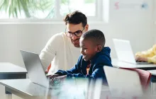 Teacher and student working together at laptop