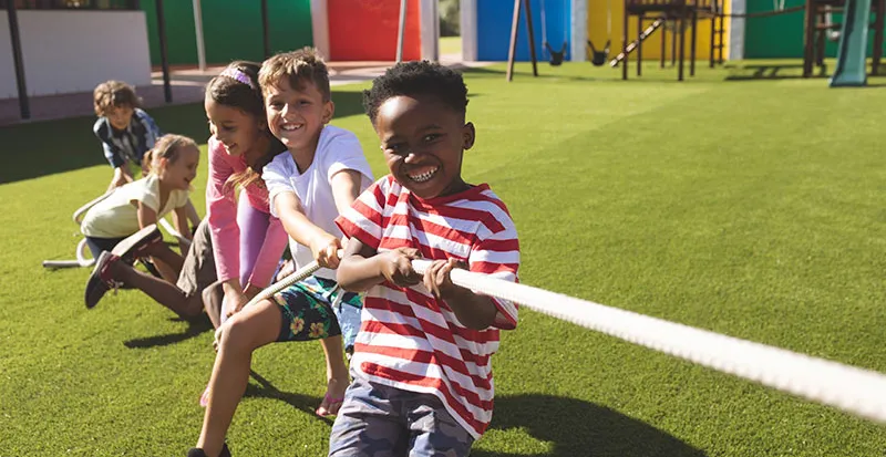 Young kids pulling on a rope together outside