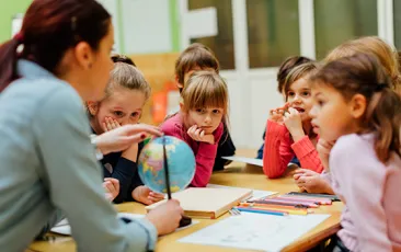 Social studies teacher with a globe and young students