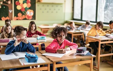 Happy elementary students having a class in the classroom