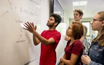 College students working a math problem at a whiteboard