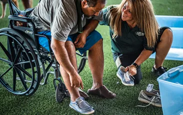 Volunteer helping homeless man in Phoenix with new shoes