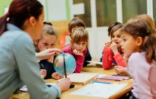 Social studies teacher with a globe and young students